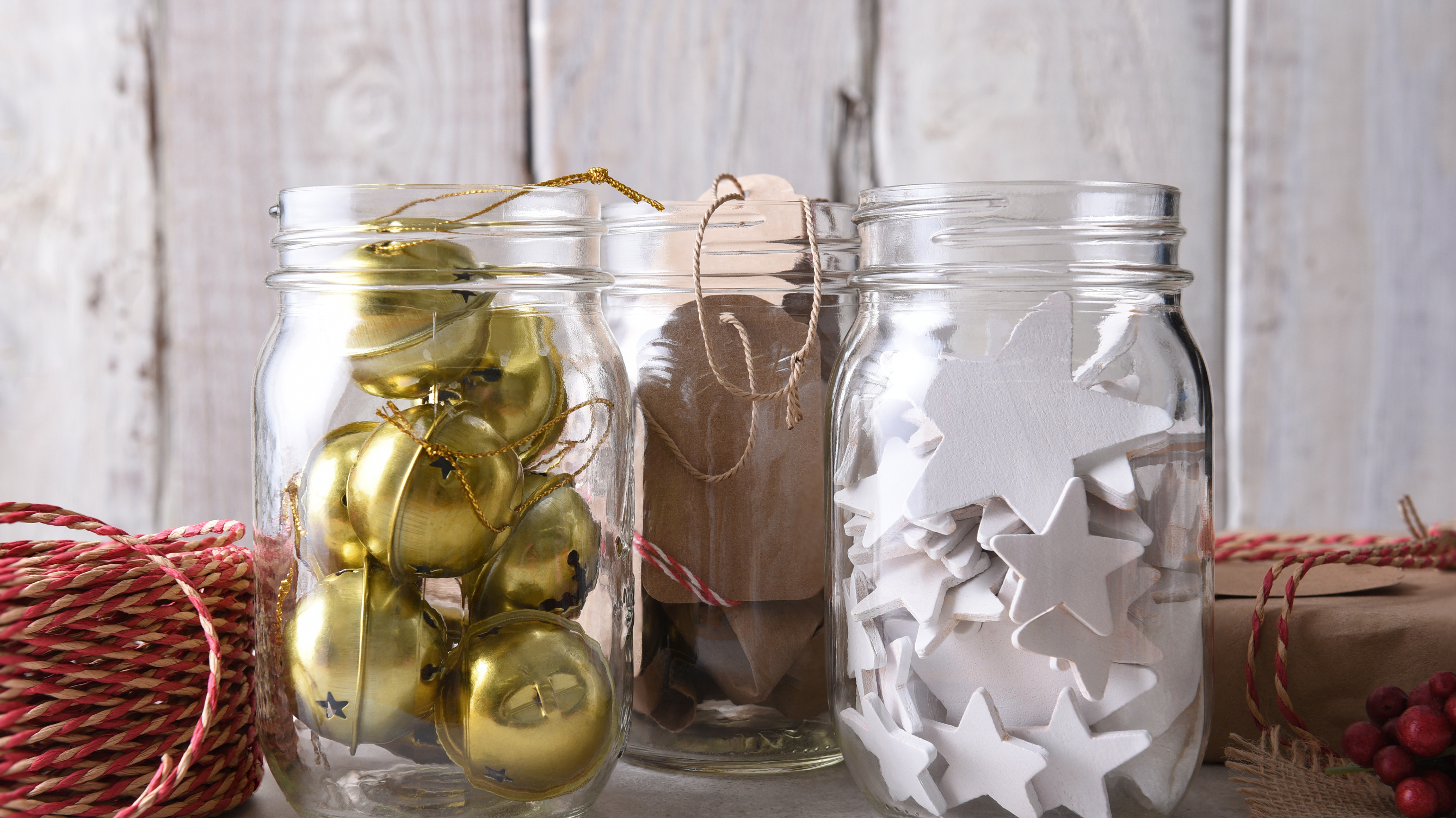 Three jars filled with various Christmas-themed decorations: stars, lights, and ornaments.